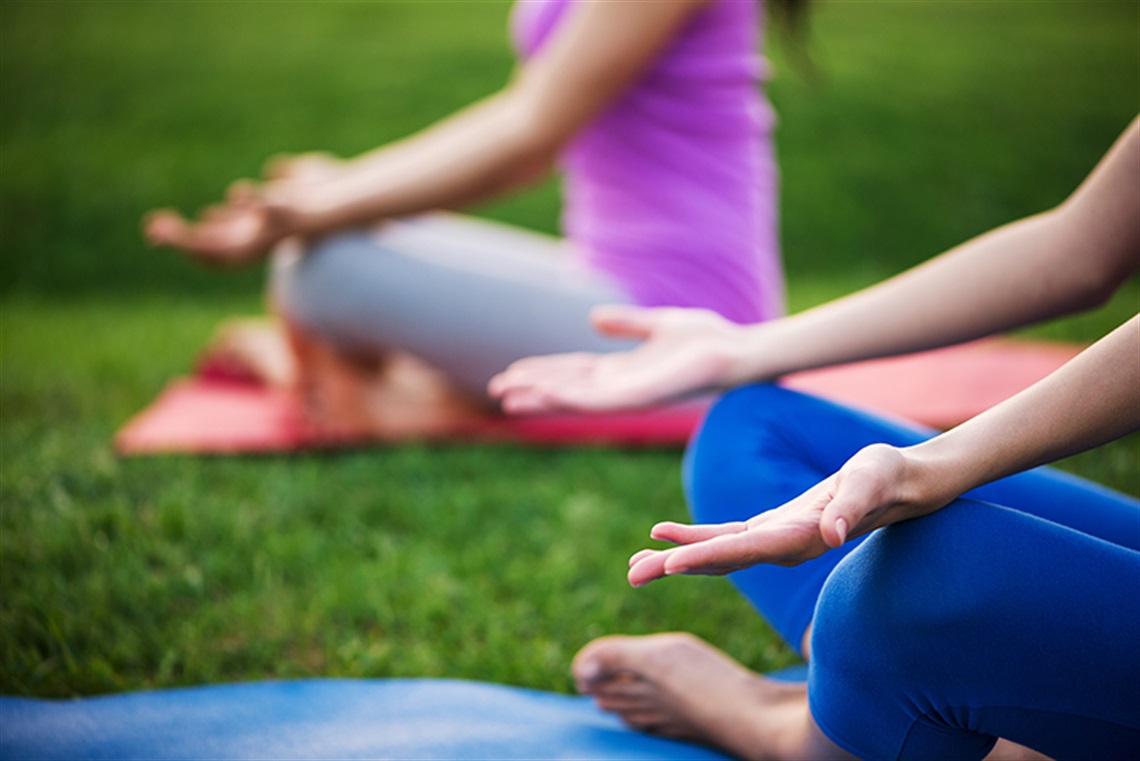 Two women on yoga mats in park