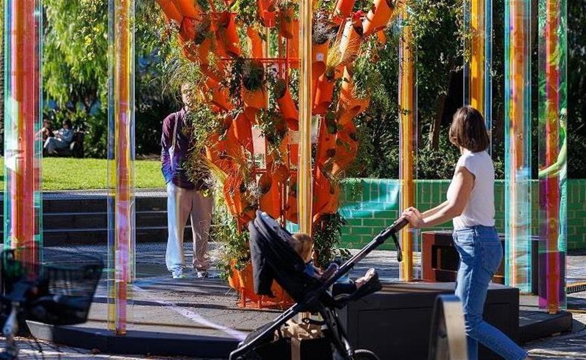 Biorhythm 2024: Woman with a baby's pusher looking at colourful statue in a park.