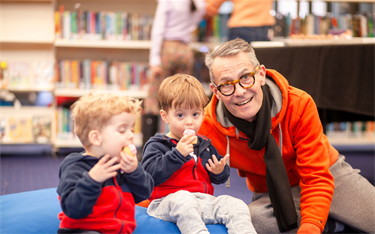 Man with two young boys eating cupcakes