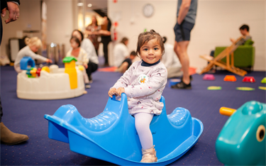 Young girl riding blue see saw